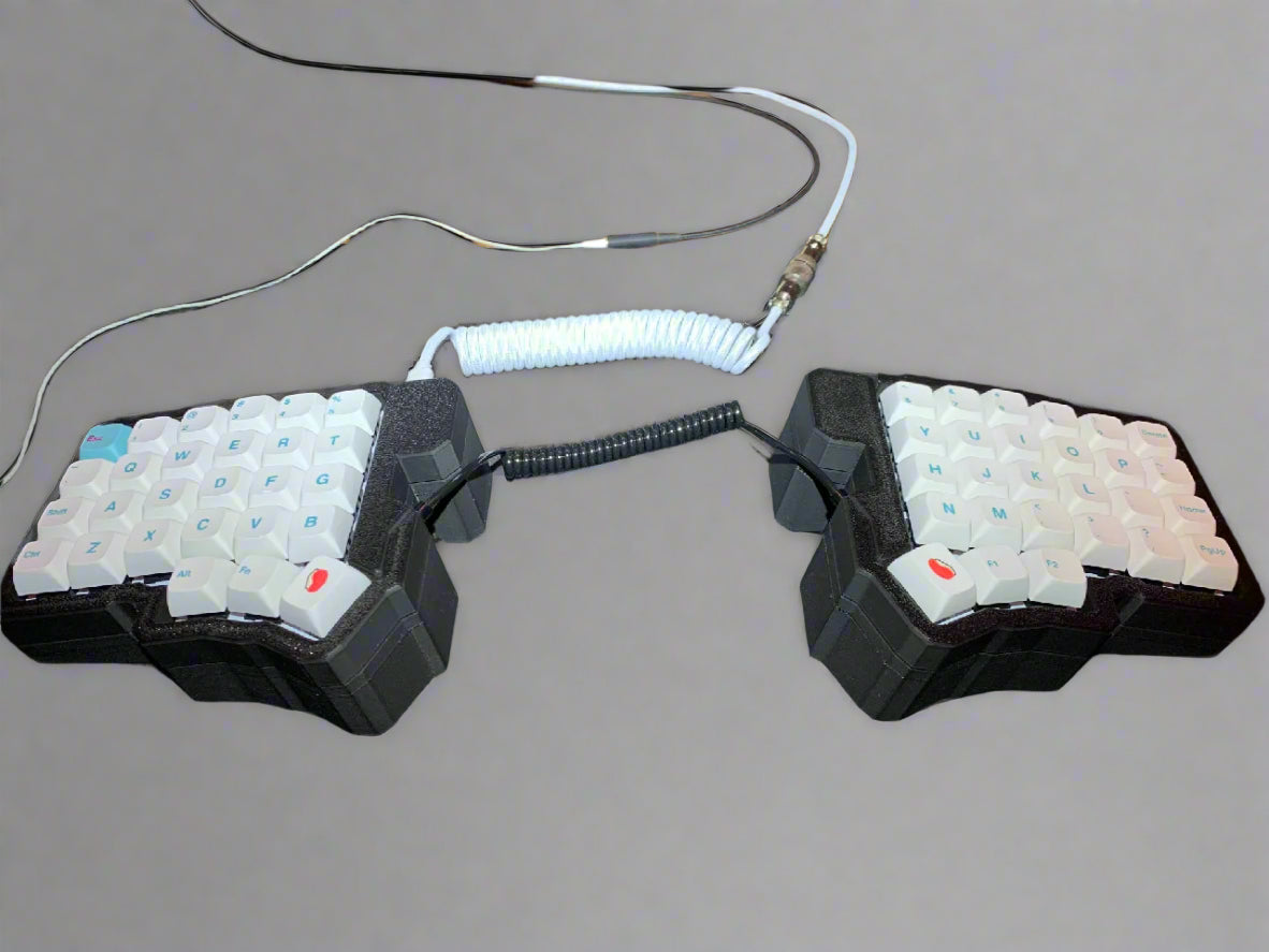 Pair of mechanical keyboard keycaps on a desk with visible cables.