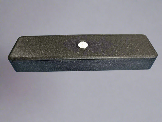 Black rectangular object with a central hole on a blue background